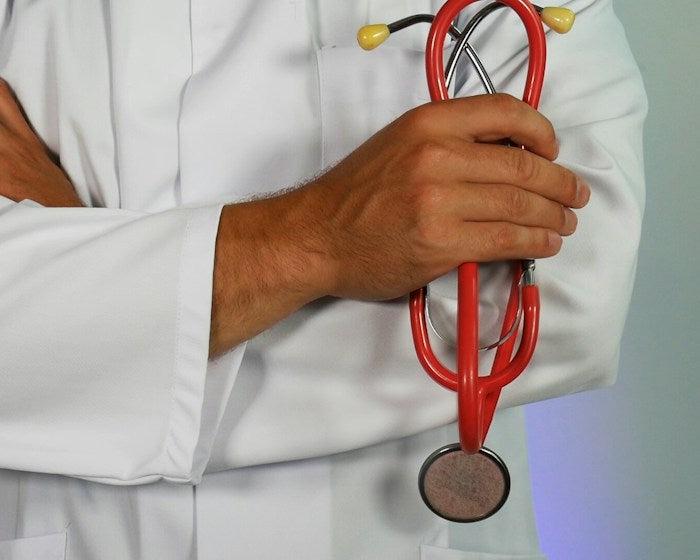 Health care: a doctor in a white coat holding a red stethoscope