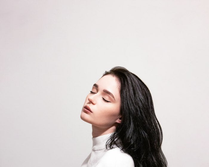 Hair care: portrait with long healthy hair on a pale background